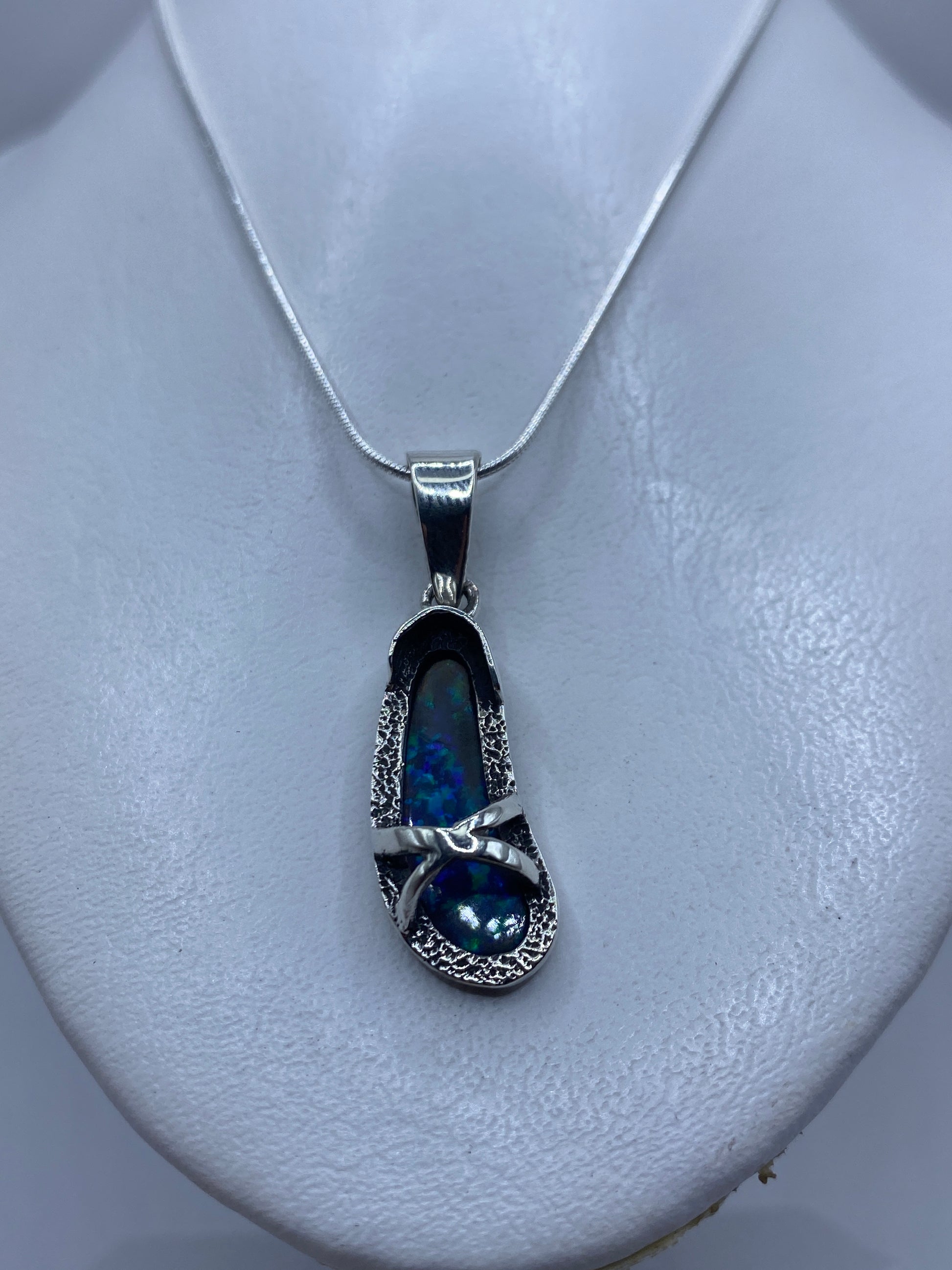 Dije de plata .950 con ópalo de fuego azul sobre pecho blanco, mostrando tamaño real de 4.5 cm