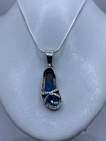 Dije de plata .950 con ópalo de fuego azul sobre pecho blanco, mostrando tamaño real de 4.5 cm