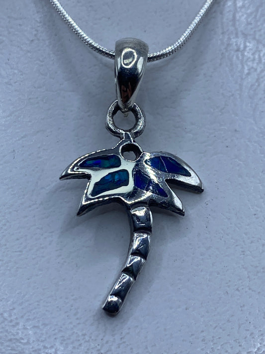 Dije de plata .950 con ópalo de fuego azul engastado a mano, colgando de cadena de plata en el cuello