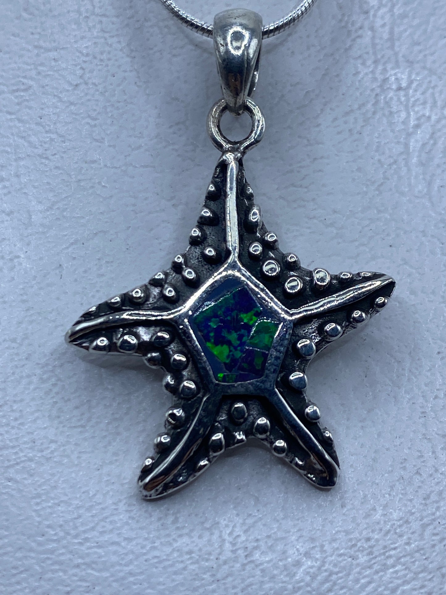 Dije estrella de plata con ópalo de fuego azul, colgando de cadena de eslabones