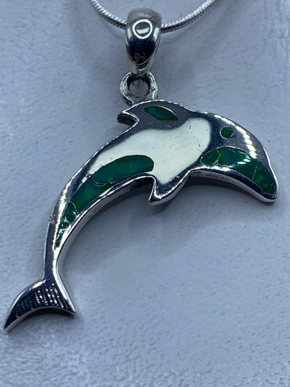 Dije de plata en forma de delfín con ópalo de fuego verde limón engastado, colgando de una cadena de serpentín