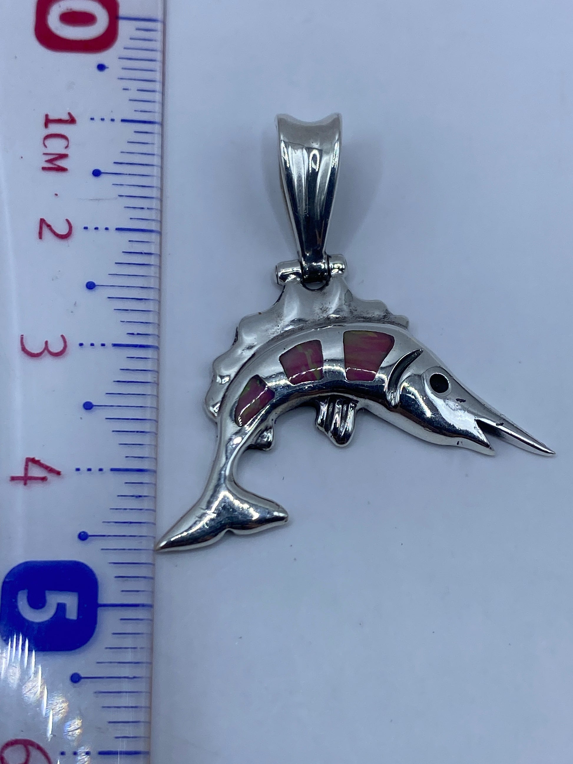 Medición del dije con regla: 4.5 cm de largo — tamaño perfecto de bolsillo