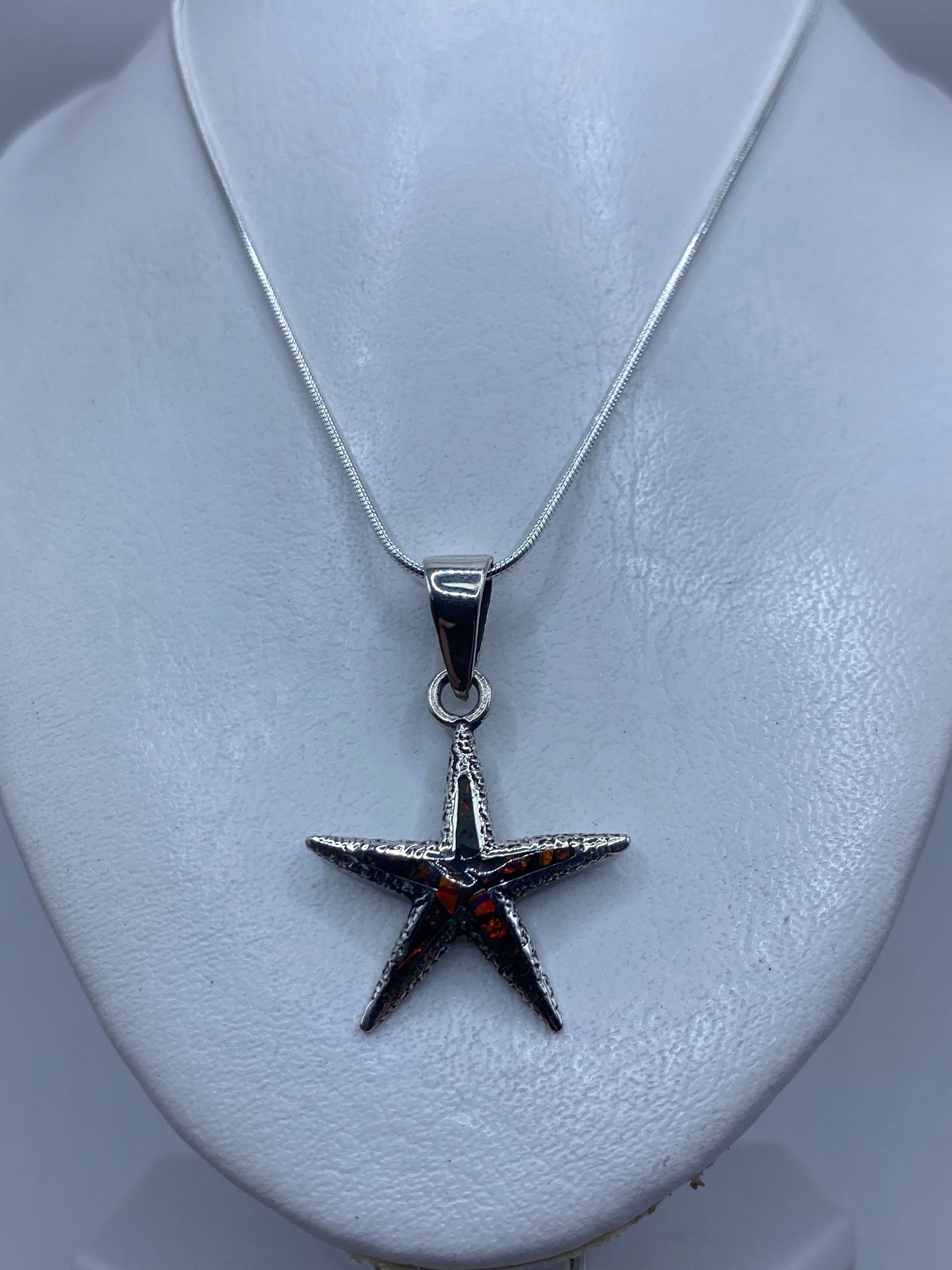 Ópalo de fuego multicolor en tonos naranja, verde y violeta engastado en la estrella