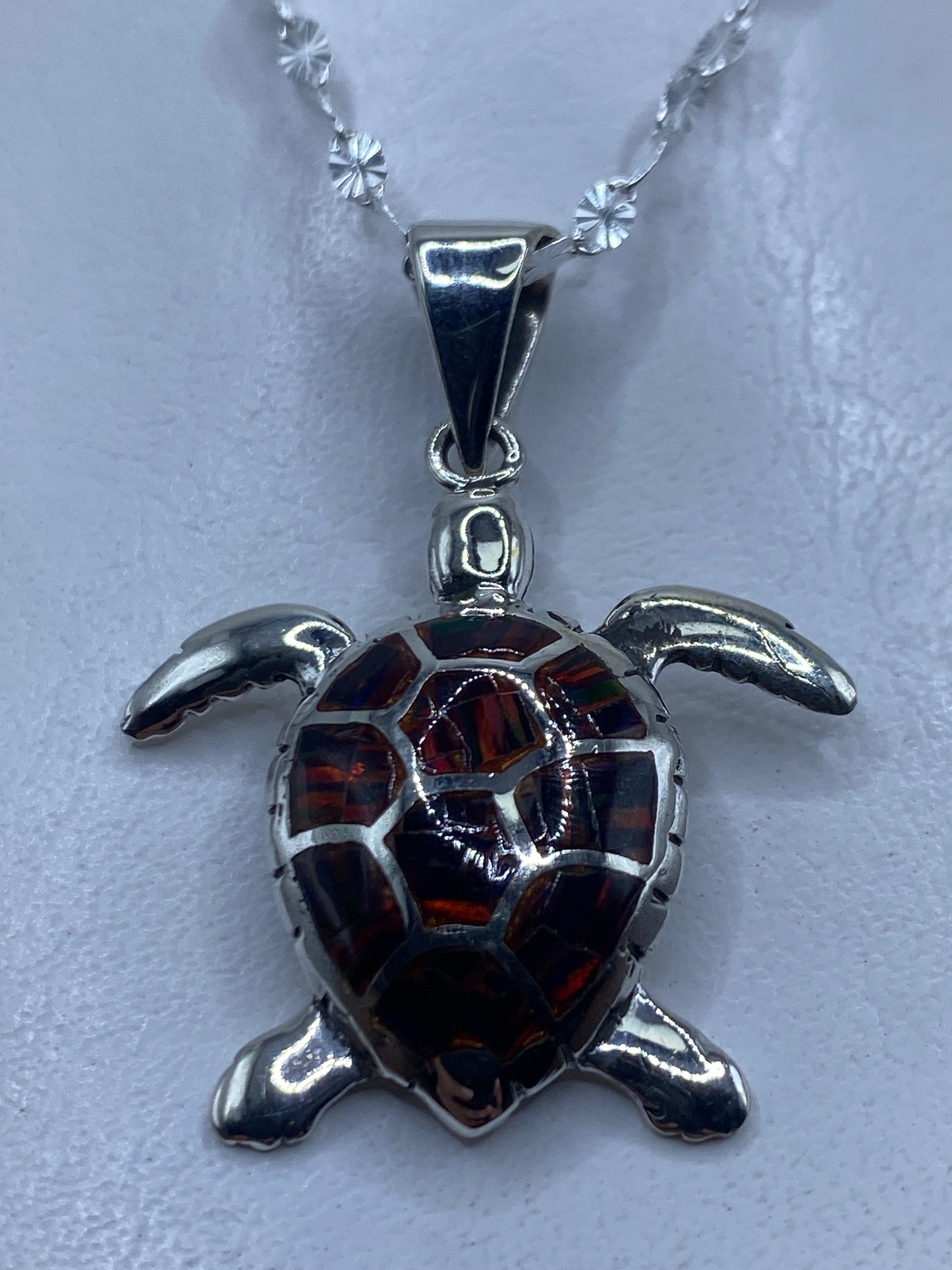 Dije tortuga en plata .950 con ópalo de fuego multicolor rojo y naranja, colgando de cadena de plata delgada