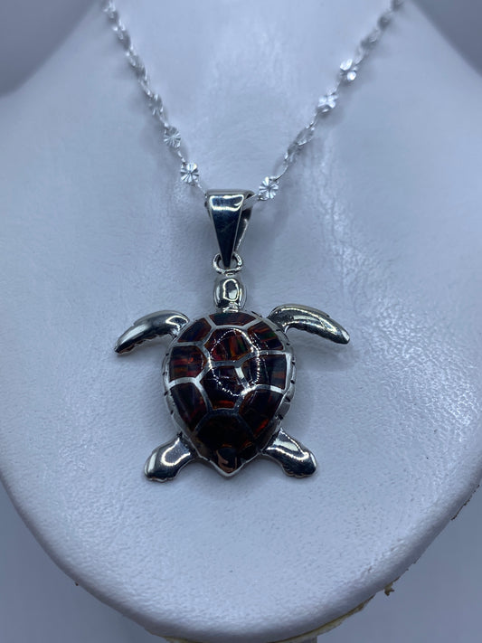 Detalle frontal de la tortuga: caparazón con ópalo de fuego y patas en plata pulida
