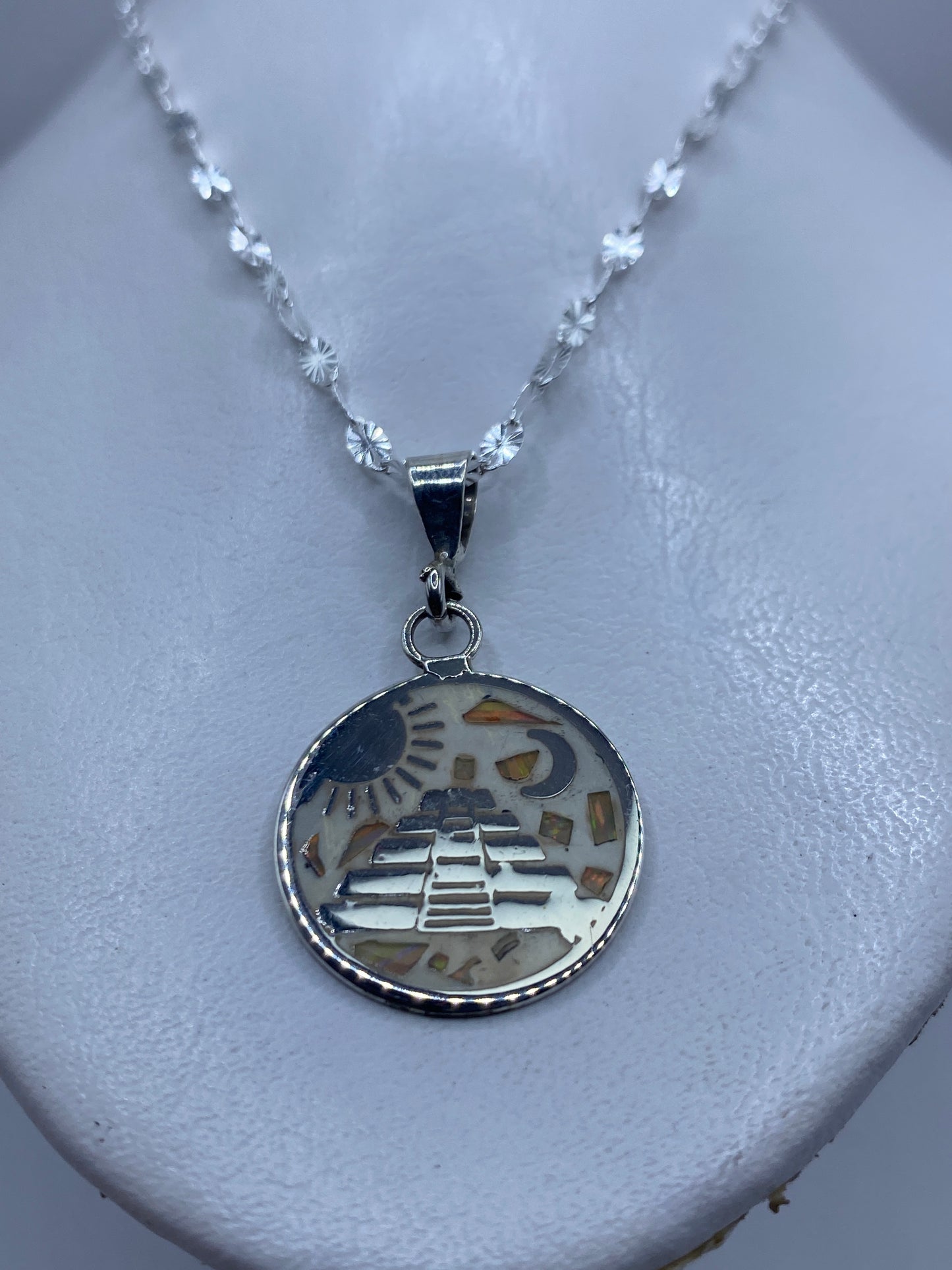 Detalle del engaste de ópalo de fuego multicolor en el dije de plata Taxco