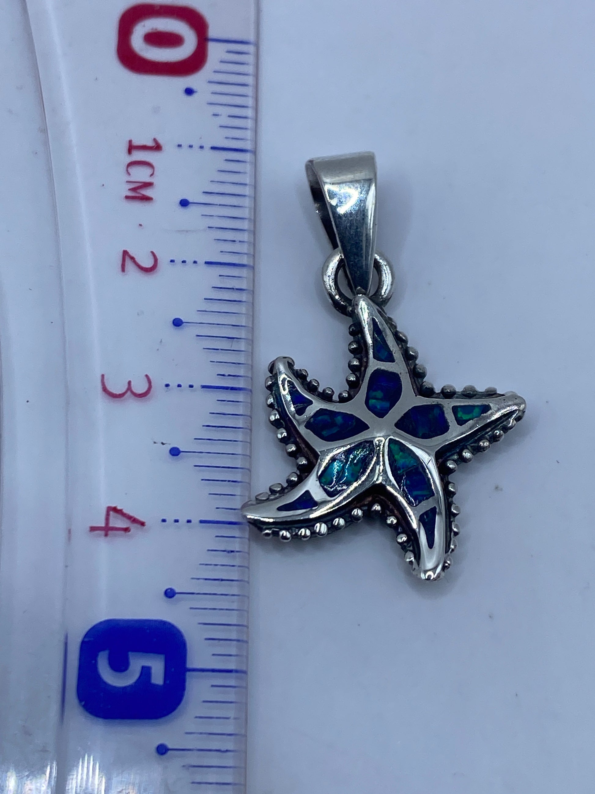 Dije en escala junto a regla: 4.3 cm de largo, con sello .950 visible en la plata