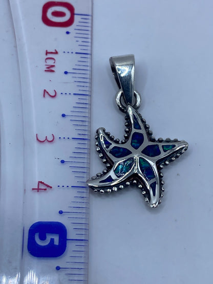 Dije en escala junto a regla: 4.3 cm de largo, con sello .950 visible en la plata