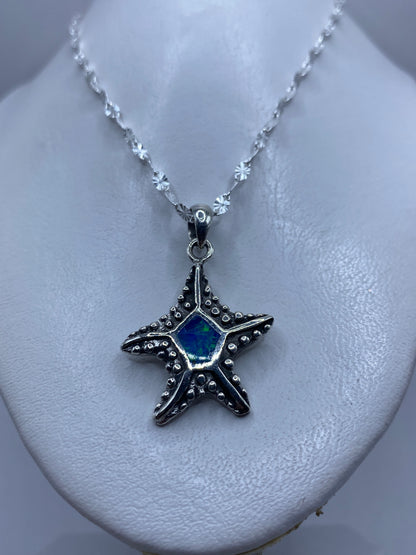 Estrella de mar vista de frente mostrando el ópalo azul engastado en el centro y el granulado artesanal