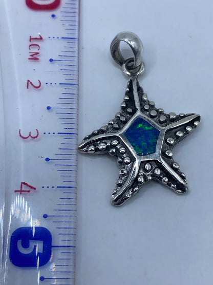 Dije estrella de mar en balanza de precisión junto a regla, 4.2 cm de largo, 3.8 gramos