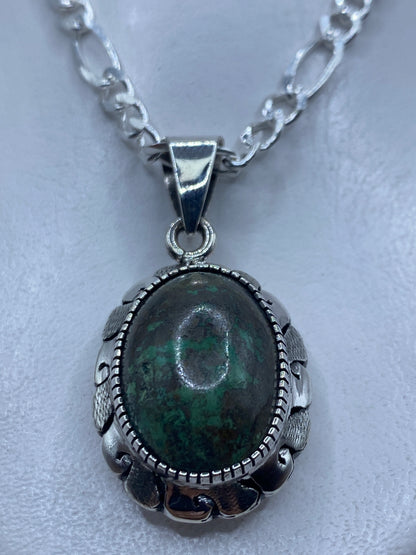 Dije de plata con piedra engastada de 4.9 cm, colgado sobre fondo blanco