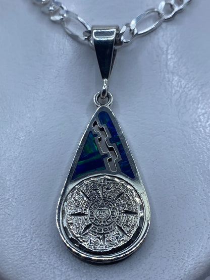 Dije de plata .950 con Piedra del Sol azteca e incrustaciones de ópalo de fuego azul