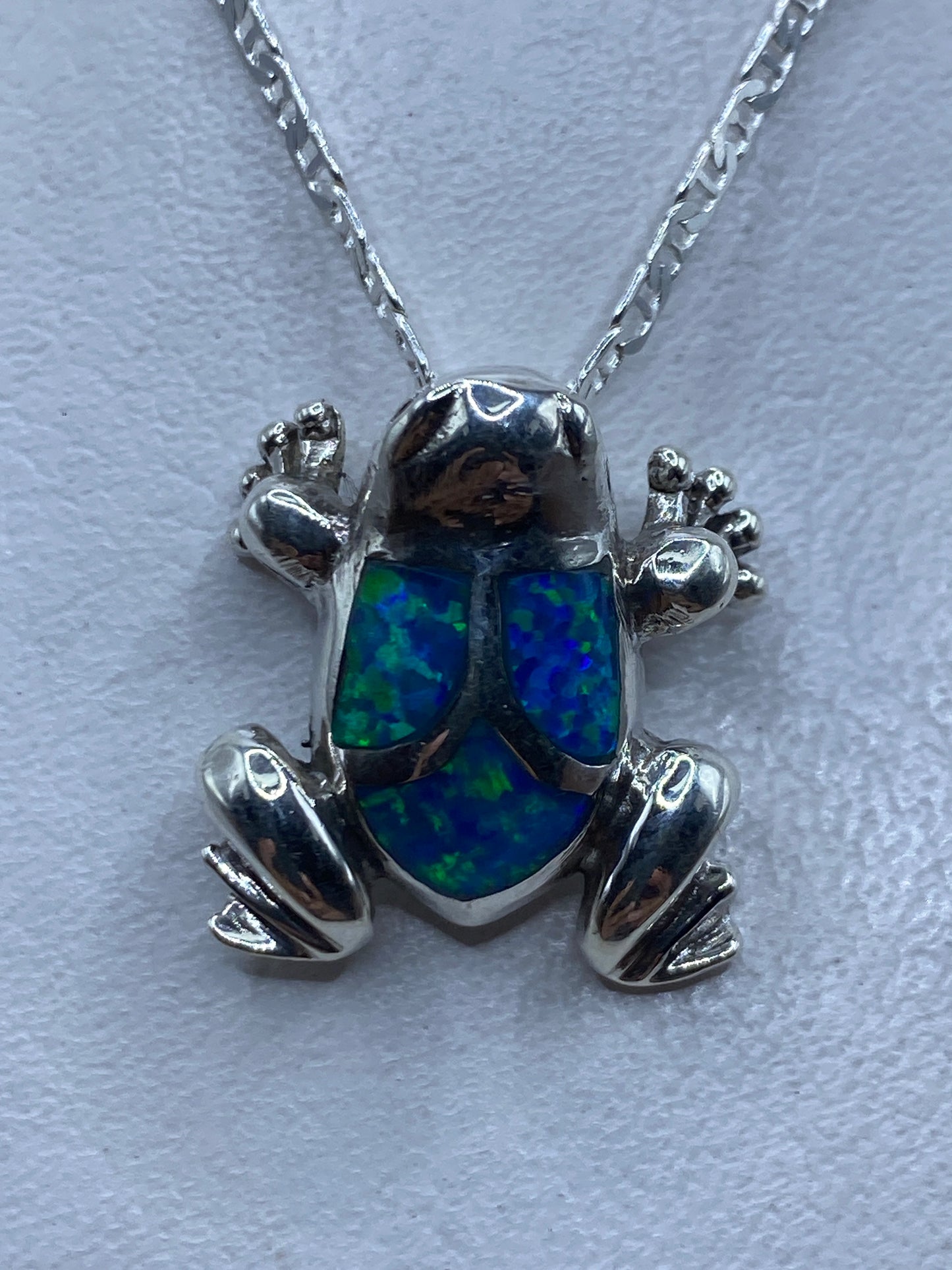 Dije sapo de plata .925 con ópalo de fuego azul engastado, colgando de cadena de plata