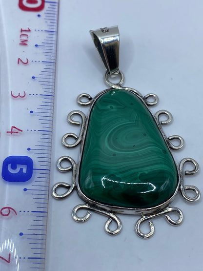 Reverso del dije de plata mostrando el Quinto .950 y espirales ornamentales