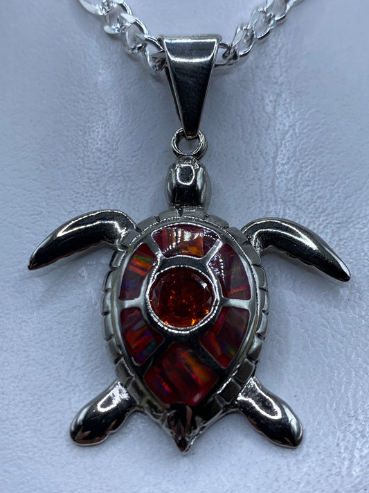 Dije de plata con forma de tortuga marina y ópalo de fuego naranja engastado en el centro