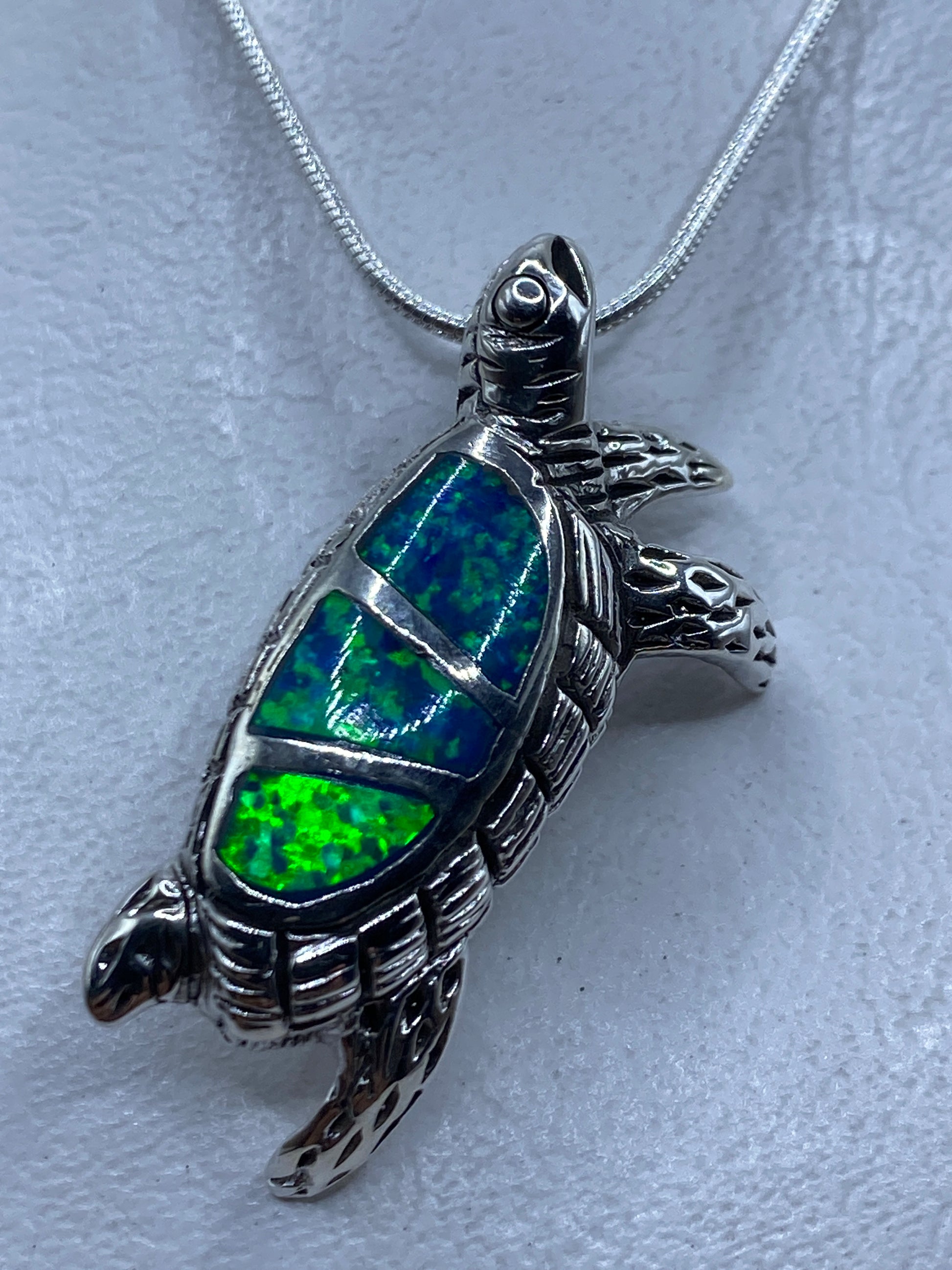 Dije de plata en forma de tortuga con ópalo de fuego azul engastado en el caparazón