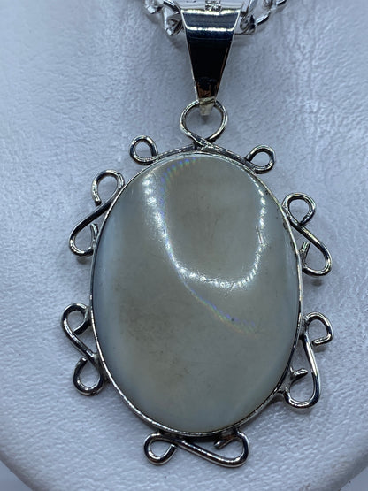 Dije de plata .950 con perla natural engastada, mostrando el marco ornamentado con argollas de filigrana