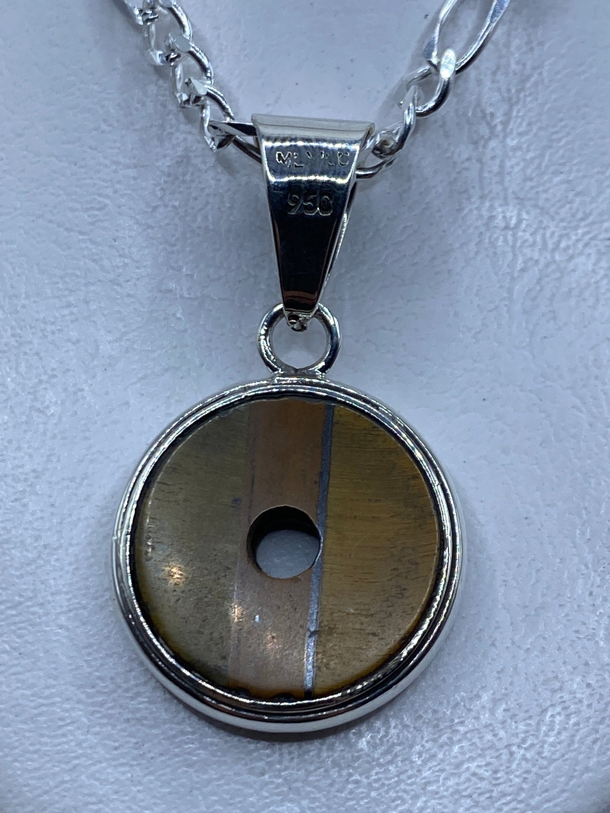 Dije redondo de plata .950 con piedra natural color café engastada, colgante sobre cadena de eslabones
