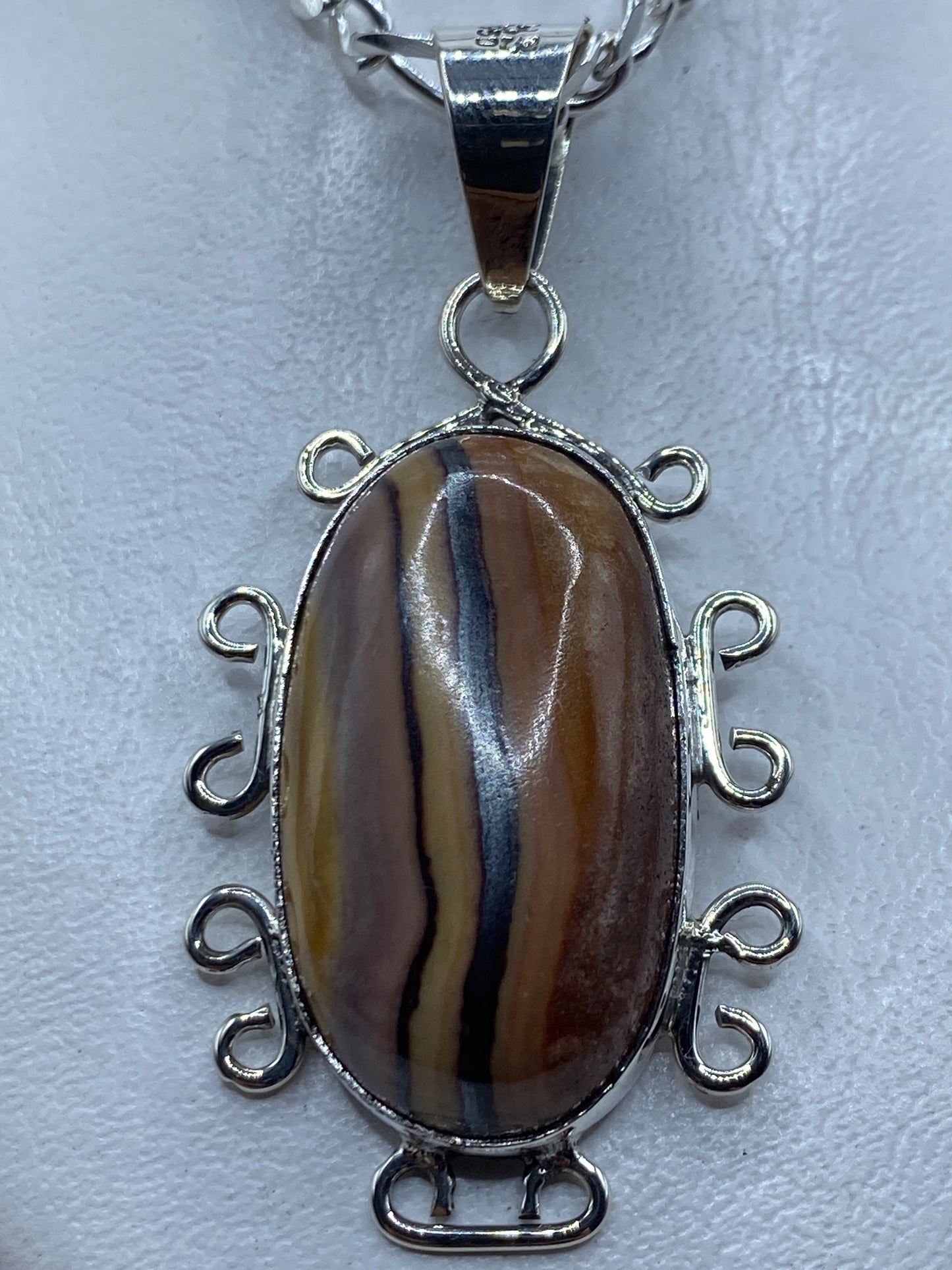 Dije de plata .950 con piedra café natural y engarce decorativo, largo 6.2 cm, colgado de cadena