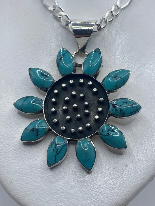 Dije floral de plata .925 con diez pétalos de turquesa azul cielo en mano de mujer