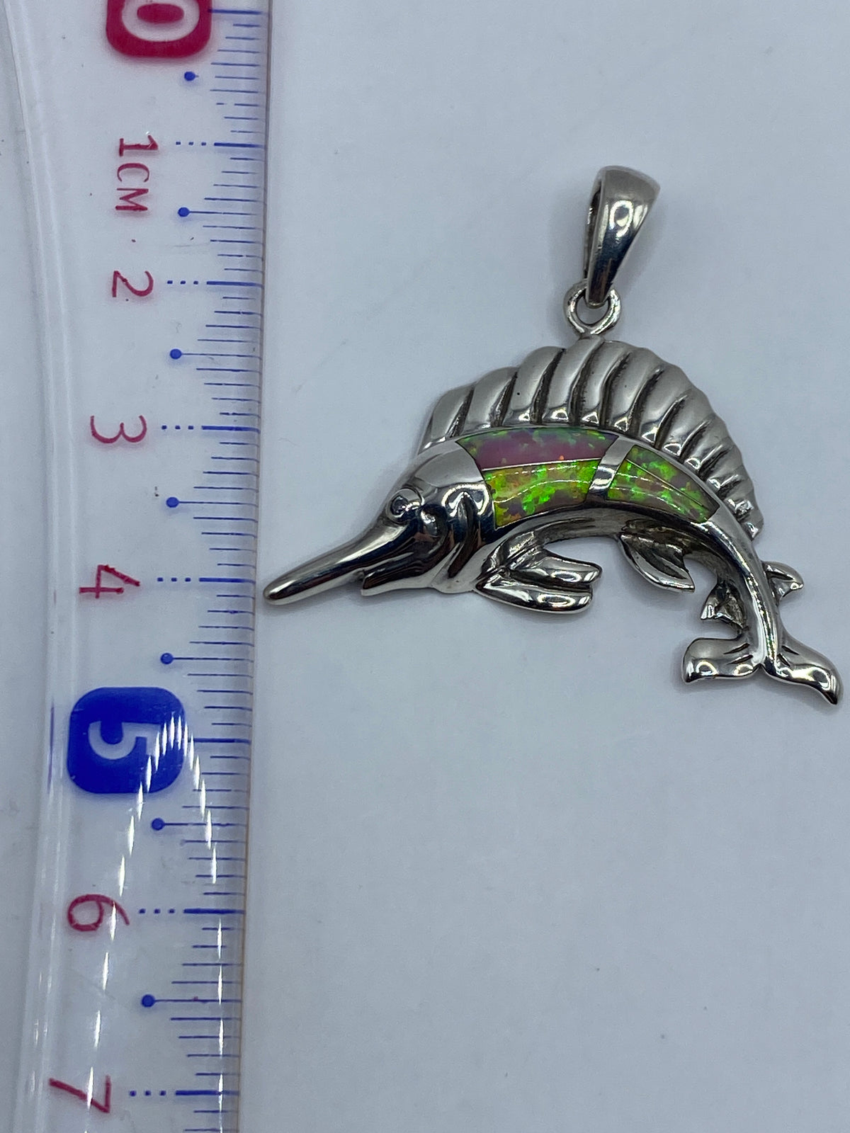 Reverso del dije pez mostrando el acabado en espejo y marca de plata