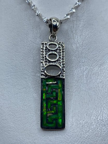 Dije de plata con ópalo de fuego verde limón y diseño geométrico prehispánico, colgando de cadena plateada