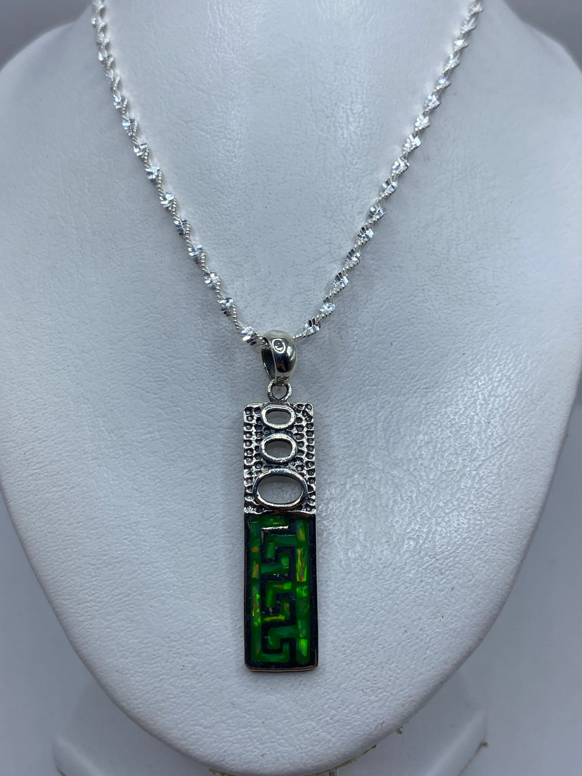 Detalle de la incrustación a mano del ópalo de fuego verde limón en la plata .950