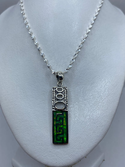 Detalle de la incrustación a mano del ópalo de fuego verde limón en la plata .950