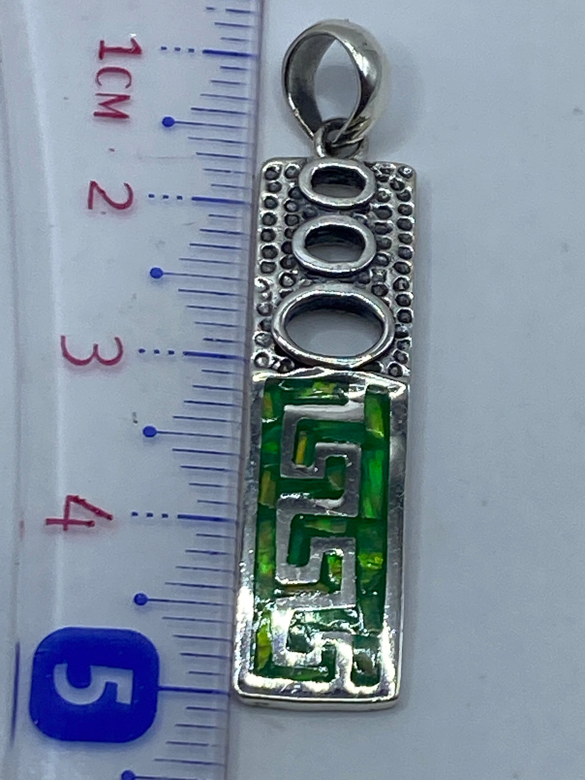 Dije sobre regla milimétrica: 5.2 cm de largo, mostrando el Quinto 950 grabado en la parte posterior