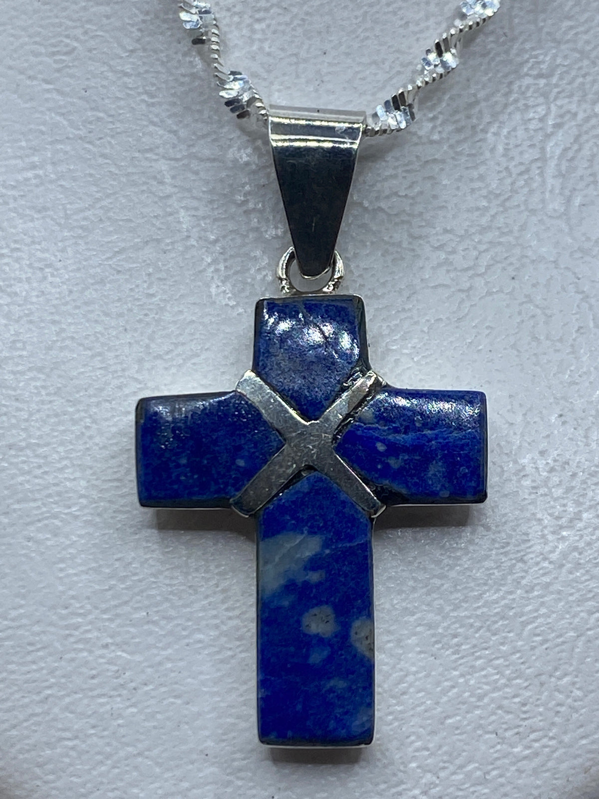 Dije cruz de plata .950 con lapislázuli azul profundo, colgante sobre fondo blanco