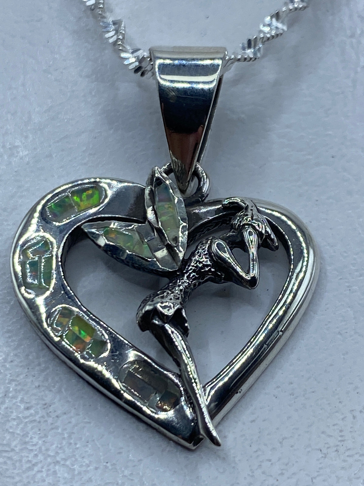 Dije de plata en forma de corazón con ópalo de fuego multicolor y serpiente enlazada