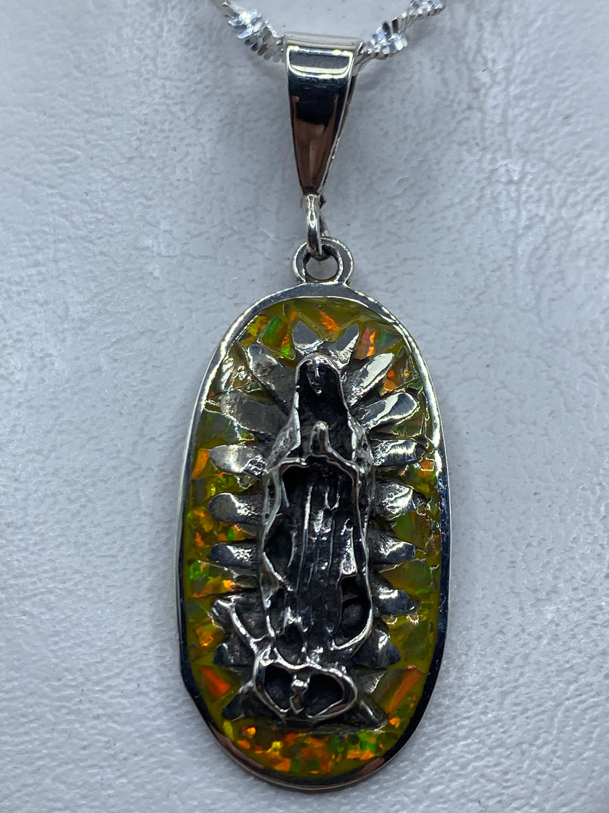 Dije Virgen de Guadalupe en plata .950 con Ópalo de Fuego amarillo, colgante sobre tela blanca