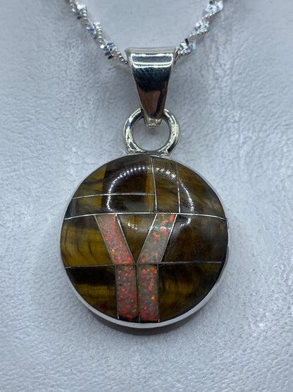 Dije de plata .950 con ópalo de fuego naranja y rojo, sobre cadena de eslabones en el pecho
