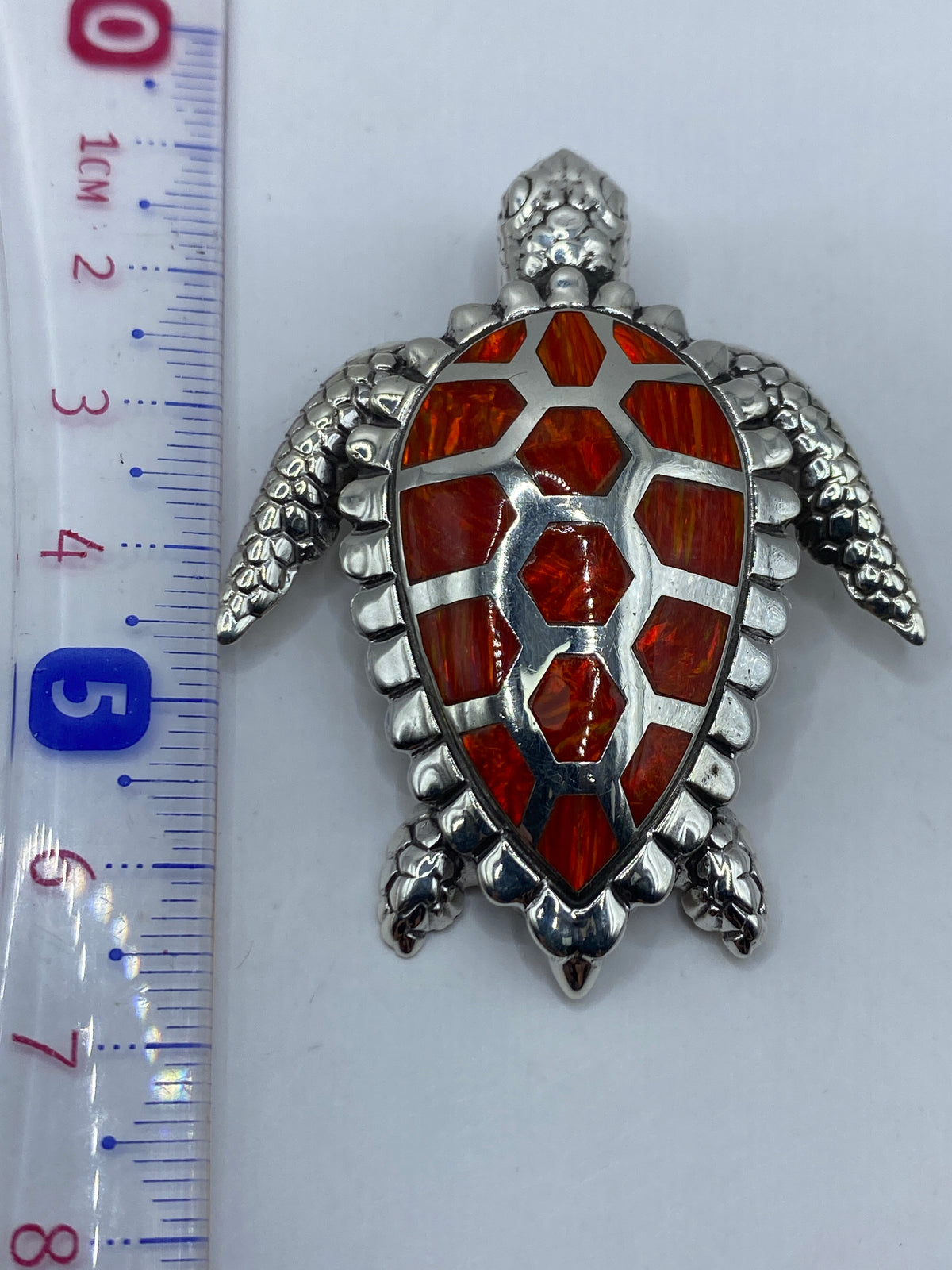 Dije tortuga en plata .950 sobre fondo blanco, con hallmark y sello de autenticidad visible