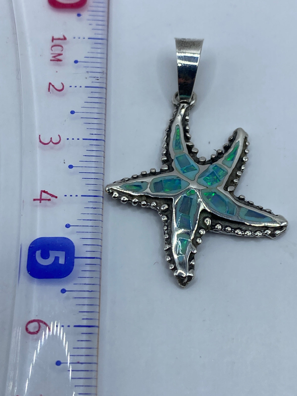 Dije de estrella marina sobre fondo gris mostrando el sello .925 en el pedúnculo