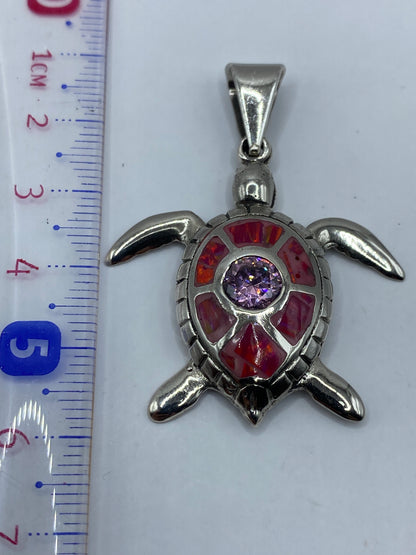 Dije tortuga sobre fondo blanco midiendo 5.6 cm de largo