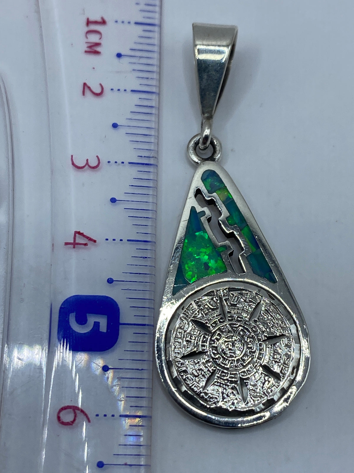 Dije colgado de cadena de plata brillante, sobre pecho