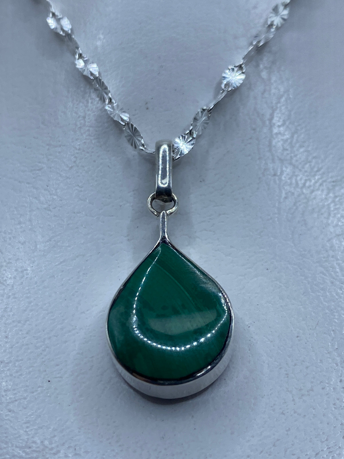 Dije de plata con malaquita verde en forma de gota, colgando de cadena plateada