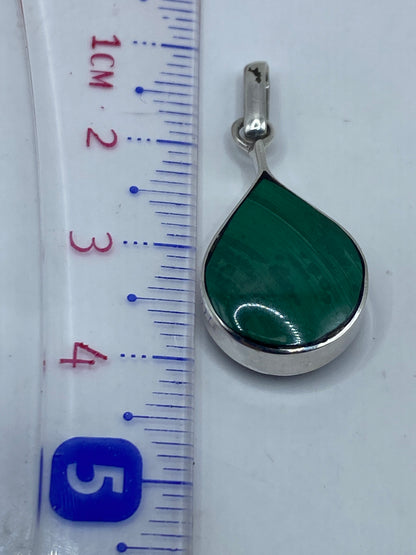Dije de plata con malaquita sobre pano blanco mostrando el acabado pulido