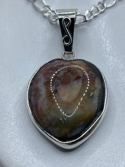 Dije de plata .950 con piedra multicolor en forma ovalada, colgando de una cadena plateada