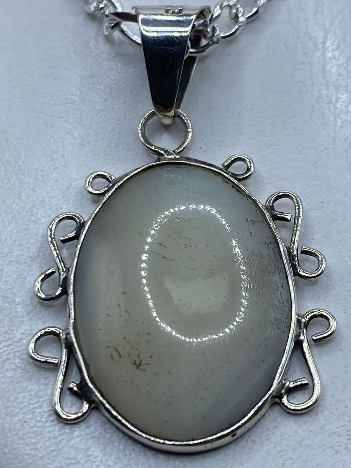 Dije de plata .950 con perla blanca engastada, colgado de cadena de plata sobre pecho