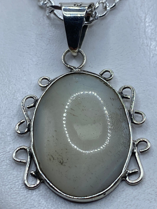 Dije de plata .950 con perla blanca engastada, colgado de cadena de plata sobre pecho