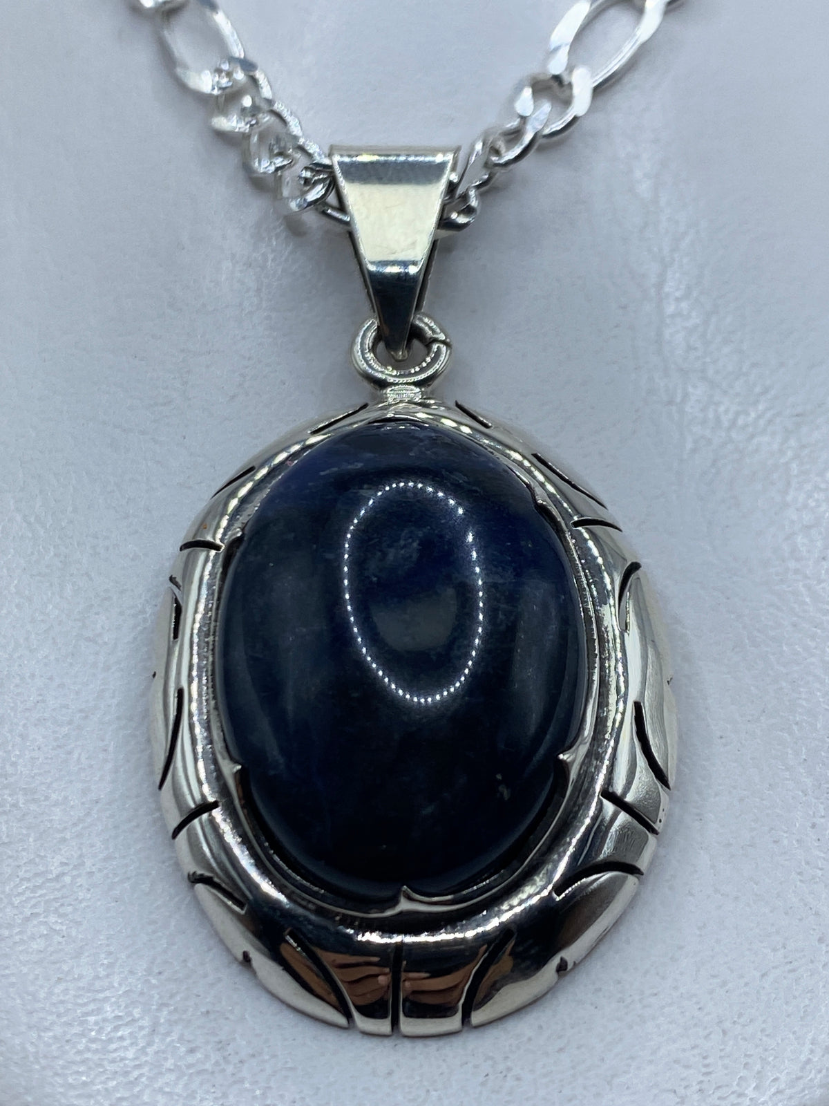 Dije de plata .950 con piedra azul en marco ovalado, colgado de cadena figaro