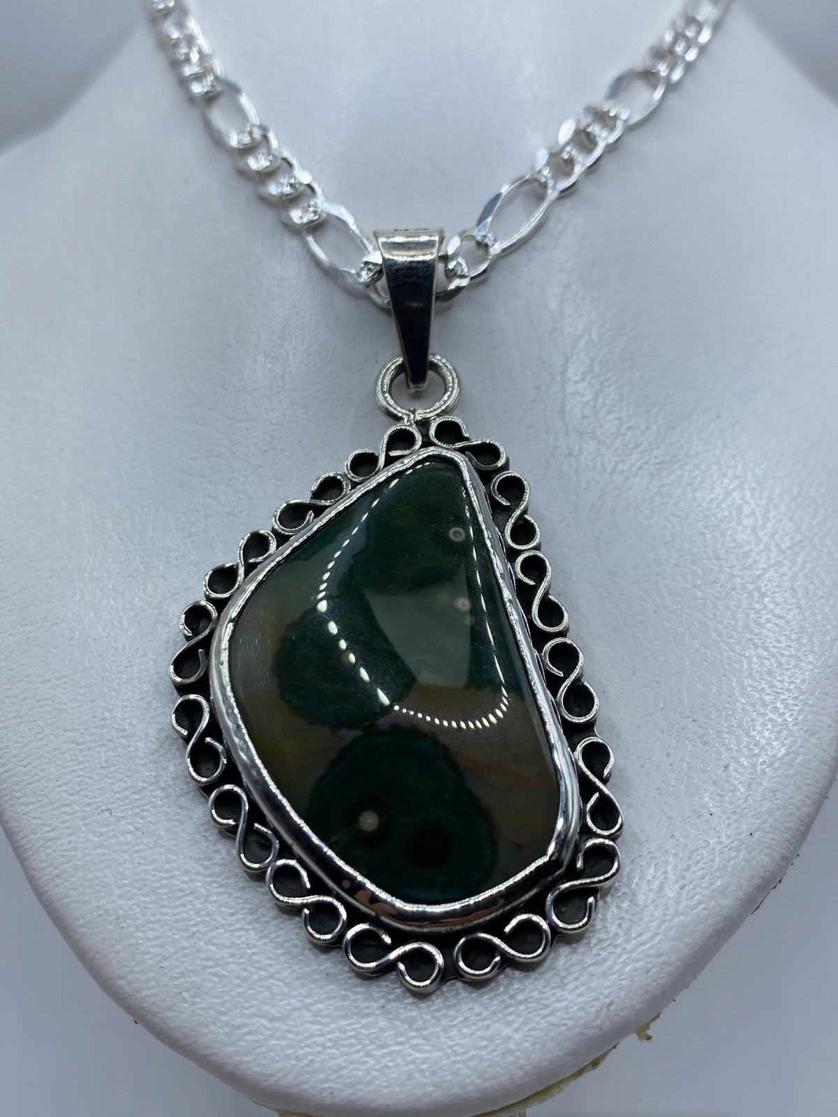 Detalle del engaste a mano de la piedra verde olivo en plata .925, mostrando la filigrana del marco