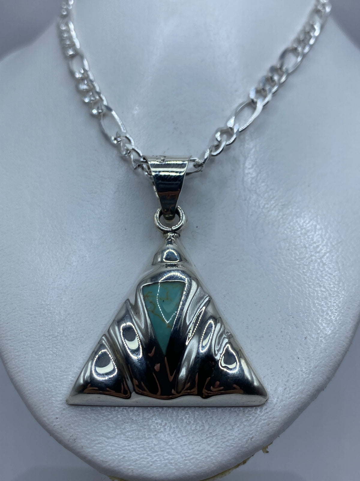 Dije de turquesa y plata visto al cuello, colgando sobre piel clara