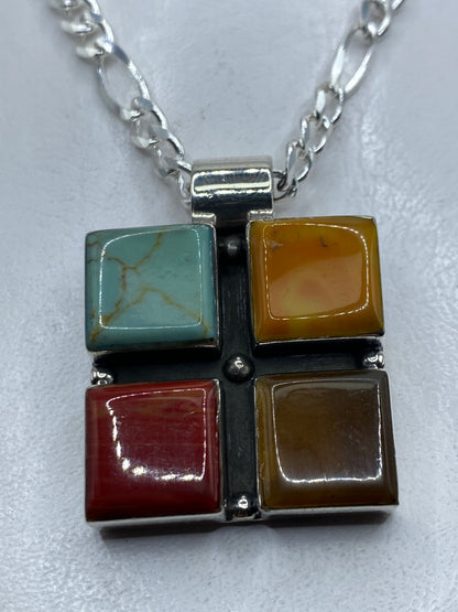 Dije de plata con cuatro piedras naturales (turquesa azul, ámbar, coral rojo, jade) engastadas a mano en Taxco