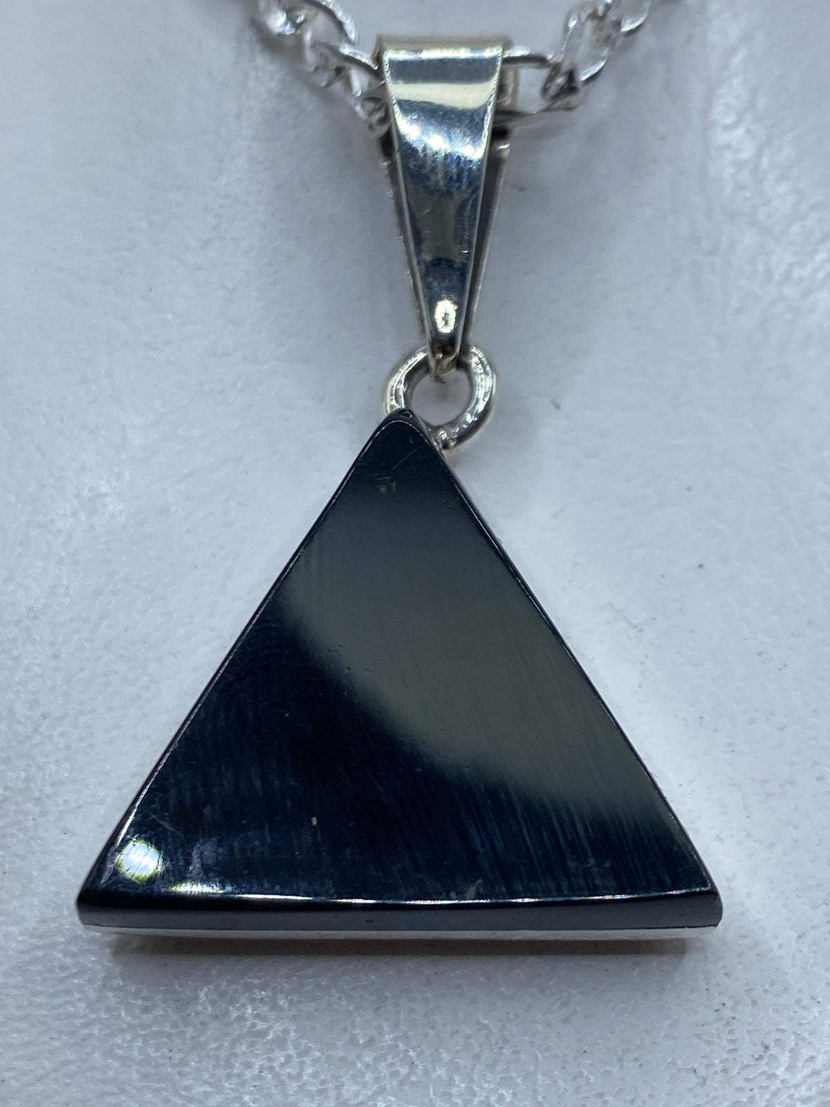 Dije triangular de plata .925 con ónix negro engastado, colgando de cadena plateada
