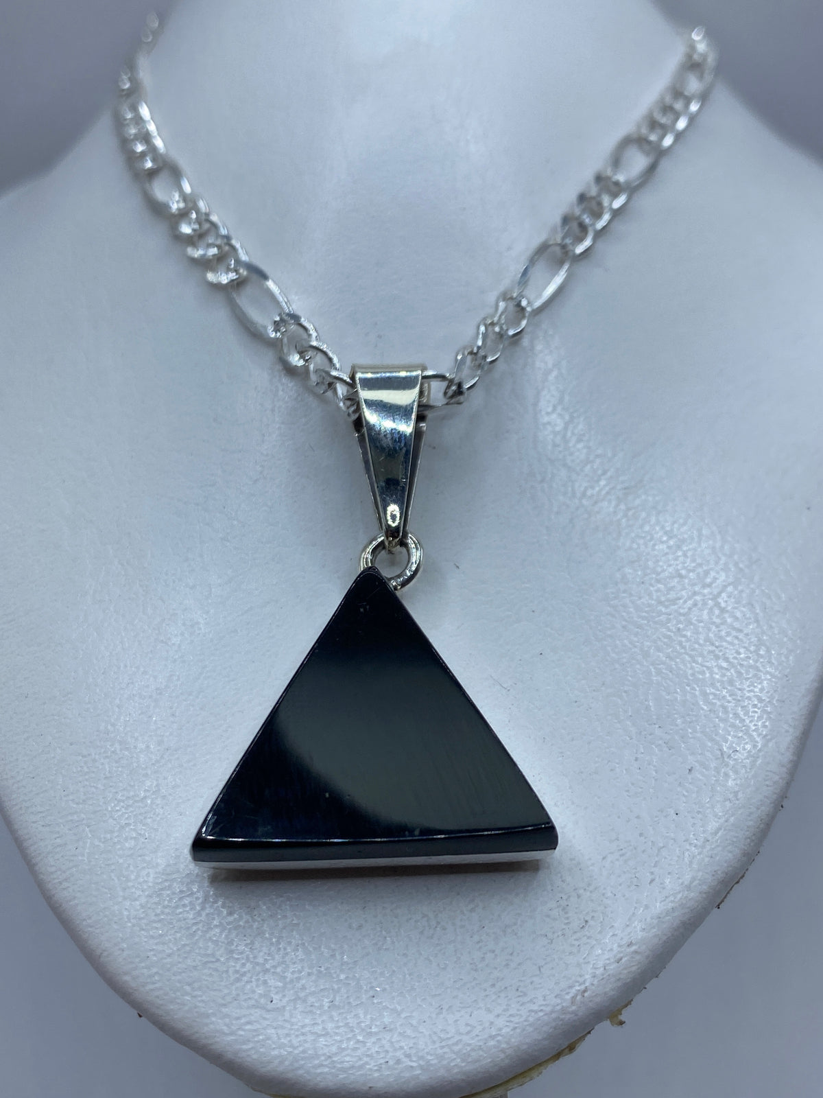 Detalle del ónix negro pulido y el engaste de plata en el dije triangular