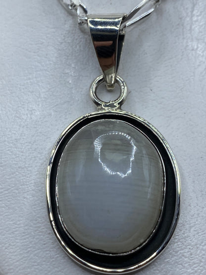 Dije ovalado de plata .925 con piedra engastada, colgado en cadena plateada