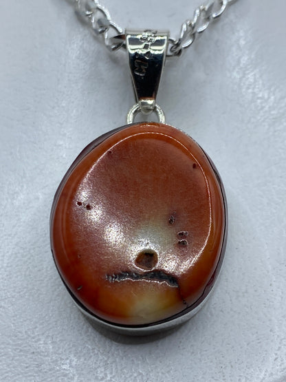 Dije de plata .950 con ámbar naranja engastado, visto al frente mostrando la piedra cálida